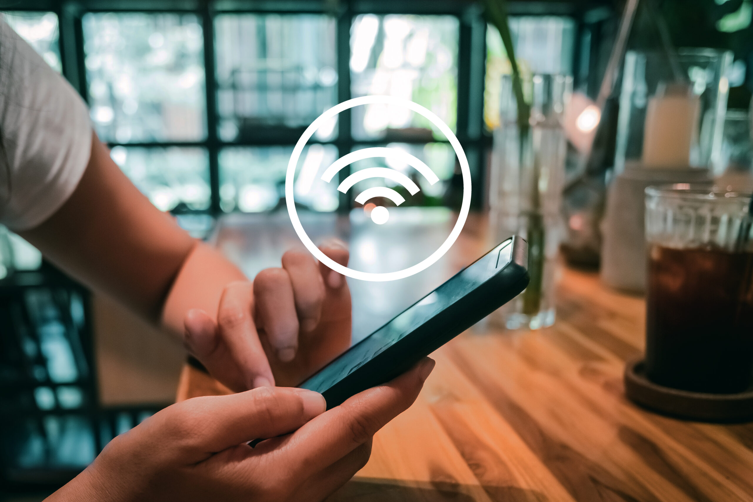 Woman hand using smartphone with wifi icon in cafe shop background. Communication social network concept.